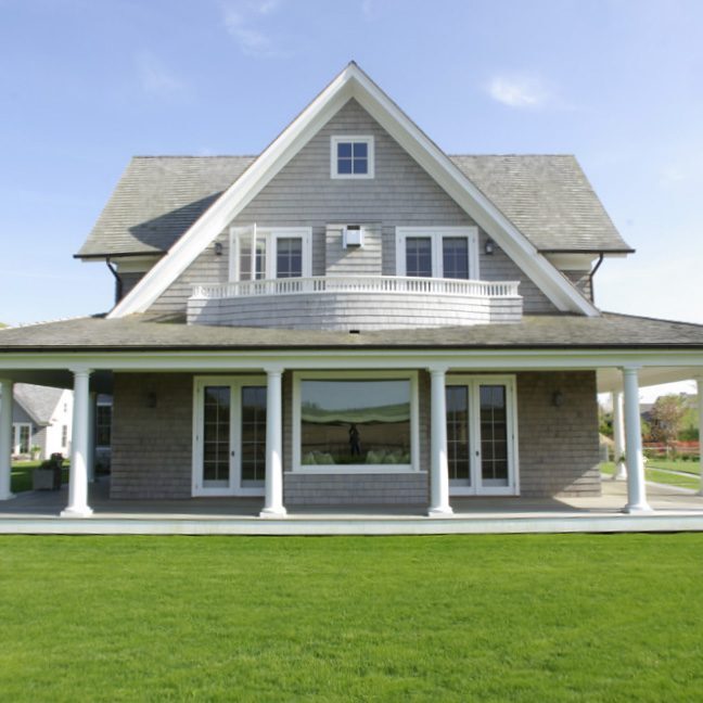 A modern two-story house with a large lawn and covered porch.